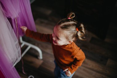 Küçük güzel kız soyunma odasında yürüyor. Bir sürü kıyafet ve kadın elbisesi arasında.