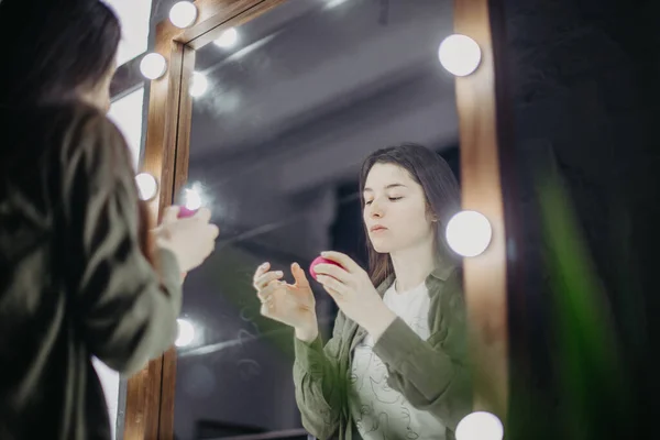 stylish girl getting makeup in the luxury beauty saloon with big mirrors and light