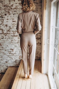 Çekici sarışın bir kadının portresi bir kadın giyim mağazasının reklamı için poz veriyor seksi bir pantolon giyip çıplak bir vücutta ceket giyiyor.