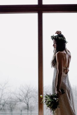 Güzel makyajlı şık bir gelinin portresi, kafasında bir çelenk ve zarif minimalist bir elbise.