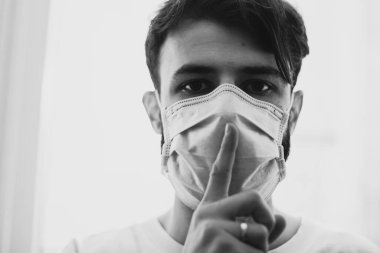 Koruyucu tıbbi maske takan genç adam, hastalığını saklayan viral bir hastalıkla evde karantinada.