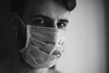 Koruyucu tıbbi maske takan genç adam virüs hastalığıyla karantinada.
