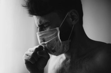 Koruyucu tıbbi maske takan genç adam virüs hastalığıyla karantinada.