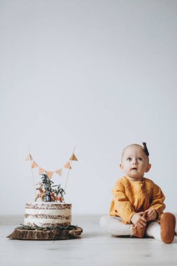Kızının doğum gününü kutluyoruz. Bugün 1 yaşında. Ailesi ona lezzetli bir pasta yaptı ve birlikte fotoğraf çektirmek için yere dikti.