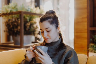 Genç ve güzel bir kız, elinde büyük bir kupa şekerli kahveyle en sevdiği kafede bir sandalyeye oturur ve her sabah kahvesini içer ve bir kız arkadaşıyla konuşur.