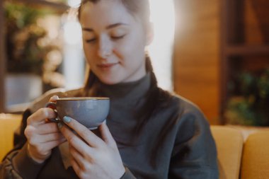 Genç ve güzel bir kız, elinde büyük bir kupa şekerli kahveyle en sevdiği kafede bir sandalyeye oturur ve her sabah kahvesini içer ve bir kız arkadaşıyla konuşur.