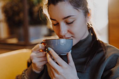 Genç ve güzel bir kız, elinde büyük bir kupa şekerli kahveyle en sevdiği kafede bir sandalyeye oturur ve her sabah kahvesini içer ve bir kız arkadaşıyla konuşur.