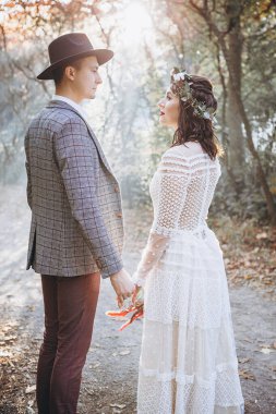 Romantik düğün anı, akşam parkında birbirine bakan bir çift yeni evli çiftin portresi. Sıcak bir düğün töreni.