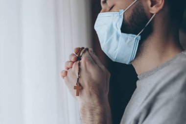 Tıbbi maske takan bir gencin portresi evde ya da pencerenin karşısındaki hastane koğuşunda karantinaya alınmış.