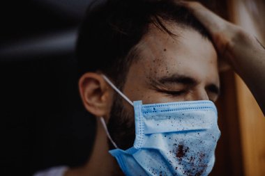Coronavirüs salgını sırasında maskeli bir adamın portresi. Tehlikeli bir viral hastalığın belirtileri: Boğaz ağrısı, öksürük, ateş.