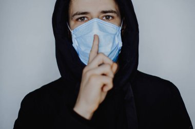 Virüs hastalığının yayılma konsepti: tıbbi maske takan genç bir adam, ama hasta hastalığını başkalarından saklıyor ve onları riske atıyor.