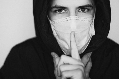 Virüs hastalığının yayılma konsepti: tıbbi maske takan genç bir adam, ama hasta hastalığını başkalarından saklıyor ve onları riske atıyor.