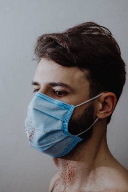 Coronavirüs salgını sırasında maskeli bir adamın portresi. Tehlikeli bir viral hastalığın belirtileri: Boğaz ağrısı, öksürük, ateş.