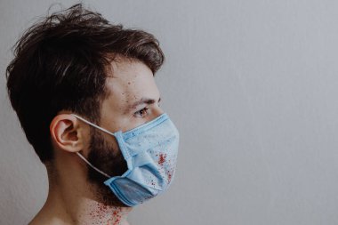 Coronavirüs salgını sırasında maskeli bir adamın portresi. Tehlikeli bir viral hastalığın belirtileri: Boğaz ağrısı, öksürük, ateş.