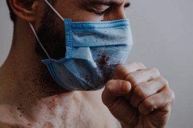 Coronavirüs salgını sırasında maskeli bir adamın portresi. Tehlikeli bir viral hastalığın belirtileri: Boğaz ağrısı, öksürük, ateş.