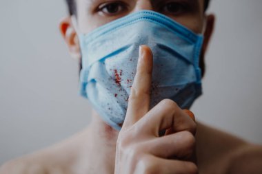 Ölümcül virüslerden korunmak için tıbbi maske takan genç ve hasta bir adamın portresi.