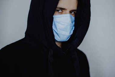 Karantina sırasında evden ayrılan herkes için zorunlu tıbbi maske. Ceket ve tıbbi maske takan genç bir adamın fotoğrafı.