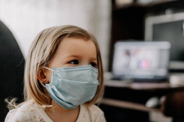 Koruyucu tıbbi maske takan bir çocuk evde tedavi edilir.