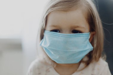 Koruyucu tıbbi maske takan bir çocuk evde tedavi edilir.