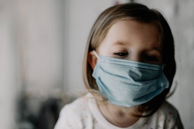 Coronavirus Covid-19 ve Hava kirliliği konsepti. Evdeki PM2.5 'u korumak için maske takan beyaz bir kız. Covid-19 koronavirüs ve salgın virüs belirtileri..