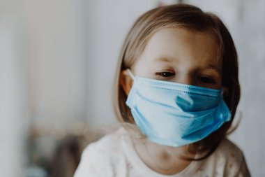 Koruyucu tıbbi maske takan bir çocuk evde tedavi edilir.