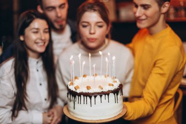 Doğum gününü evde parti pastasıyla kutlayan bir grup mutlu arkadaş.