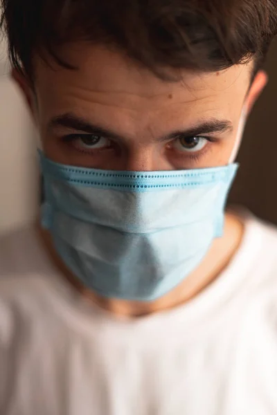 a young man wearing a mask is quarantined at home
