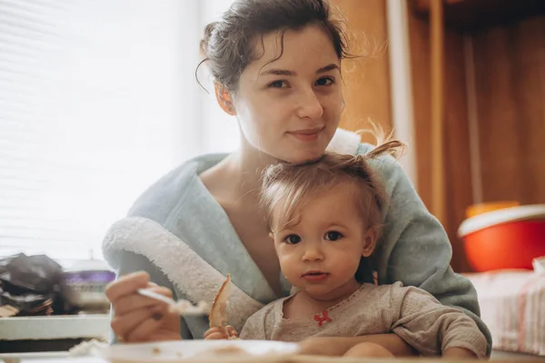 selective focus, noise effect: a pretty child girl, together with her mother have breakfast in the morning in the kitchen