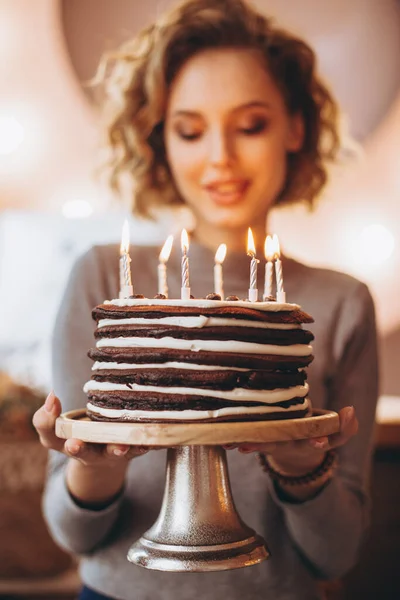 年轻迷人的金发姑娘带着华丽的模特微笑捧着蛋糕 一个快乐的生日女孩在意想不到的礼物中的情感 自制的蛋糕 点着蜡烛 有选择性地聚焦 噪音效果 — 图库照片