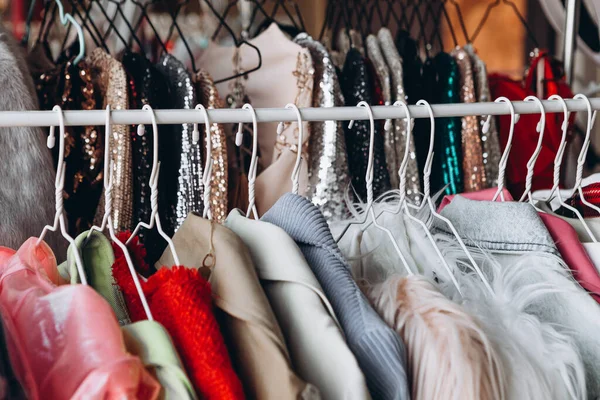 Kadın kıyafetlerinin olduğu bir mağazada yan yana duran bir sürü elbise askısı, geniş renkli kıyafetlerle dolu bir kadın mekanı.