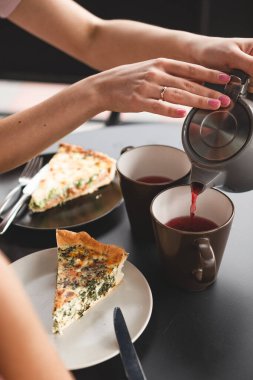 Çay fincanının ve çaydanlığın kadın ellerinde yakın plan fotoğrafını çek. Kafede sohbet ederken çay içen iki kız arkadaş.