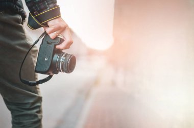 Elinde retro fotoğraf makinesi olan hippi bir adam, Moda Seyahat Yaşam tarzı şehir arka planında sisli doğa