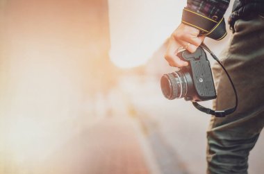 Elinde retro fotoğraf makinesi olan hippi bir adam, Moda Seyahat Yaşam tarzı şehir arka planında sisli doğa