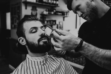 Berber dükkanında sakal ve bıyık tedavisi. Genç, sakallı, kaslı, yakışıklı berber berber dükkanında sakallı, çekici bir adamın saçını kesiyor.