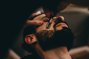 Berber dükkanında sakal ve bıyık tedavisi. Genç, sakallı, kaslı, yakışıklı berber berber dükkanında sakallı, çekici bir adamın saçını kesiyor.