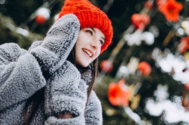 Karla kaplı bir parkta Noel ağacının önünde eko kürk ve eldiven giymiş genç ve çekici bir kadının portresi. Mutlu yeni konsept. Boşluğu kopyala