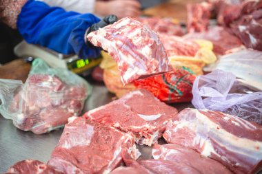 Doğal ev piyasasından seçici odak fotoğrafı. İçinde boynuzlu hayvanlar var. Satıcı kadın alıcıya bir parça et sunar.