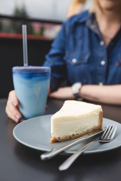 a slice of cheesecake prepared according to the classic recipe: made of shortbread cookies, butter, cream and cottage cheese. Cheesecake on a plate in a harmonious color combination with other details of a photo