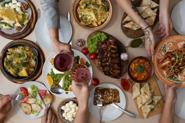 Friendly dinner. Top view of group of people having dinner together while sitting at the rustic wooden table with many plate of delicious and satisfying meals