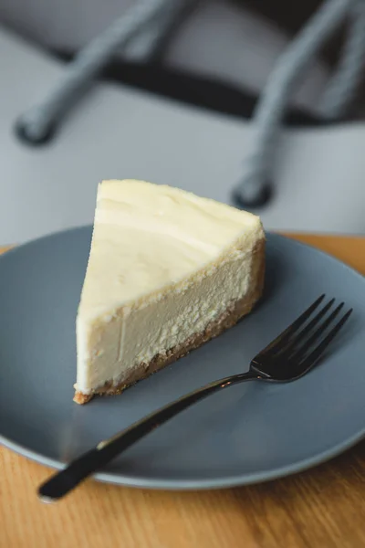 a slice of cheesecake prepared according to the classic recipe: made of shortbread cookies, butter, cream and cottage cheese. Cheesecake on a plate in a harmonious color combination with other details of a photo