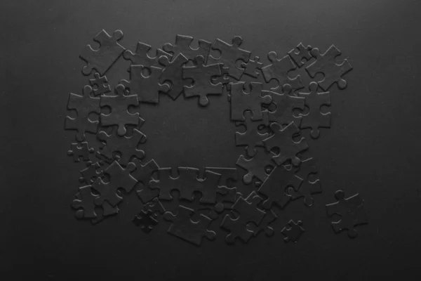 black puzzles randomly folded into a shape that forms a frame with space for your text on a dark background