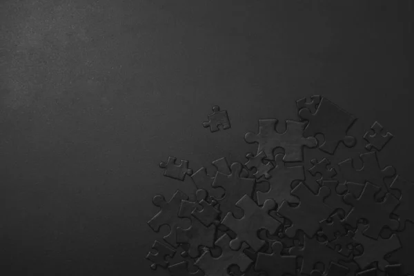 small and large black puzzles randomly scattered on a dark background with space for your text