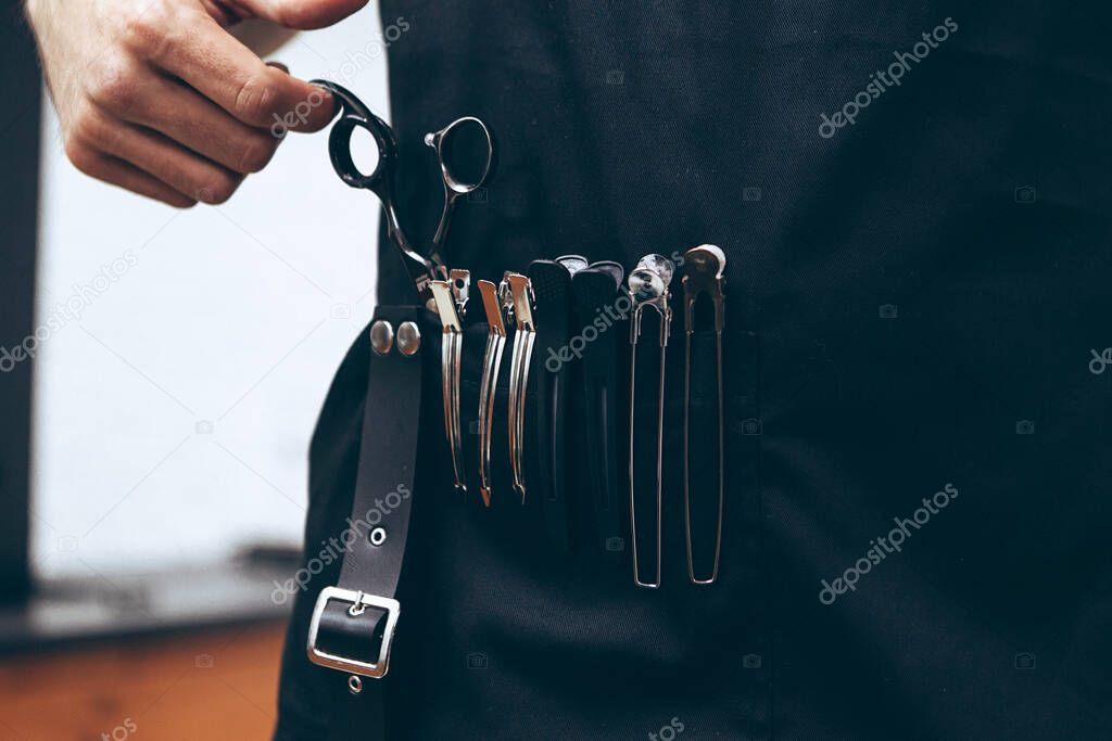 professional barber tool: sharpened scissors held by a haircut master in a modern barber shop. A concept for barbershops, beauty salons and hairdressers