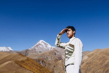 Seçici odak noktası: Beyaz milli takım elbise giymiş şık bir Gürcü. Kafkasya dağlarında düğün sırasında Gürcü damadın portresi