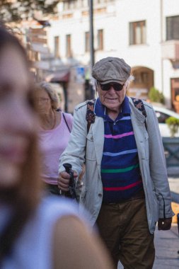 01.06.2019 Tiflis, Gürcistan: Gürcistan 'ın göbeğinde bir çubuğa yaslanmış yaşlı turist gezisini dinliyor