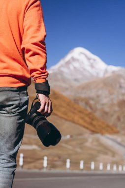 Dağcı fotoğrafçının elinin Kafkaslar 'ın arka planında DSLR kamerayla çekilmiş yakın plan fotoğrafı.