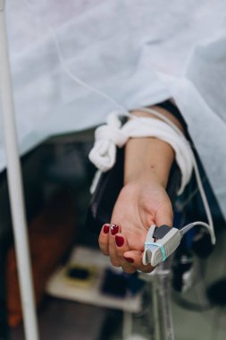 Ameliyat sırasında nabız sensörünü parmağına takan hastanın eli. seçici odak