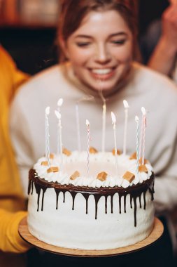 Çekici kız pastadaki mumları söndürür ve doğum gününde onu kutlamaya gelen en iyi arkadaşlarının yanında dilek tutar.