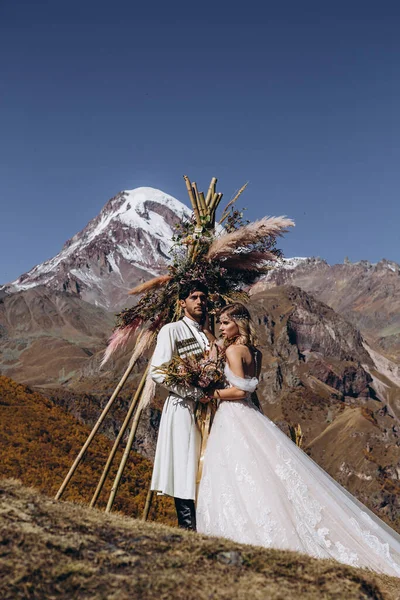 young, stylish, loving brides posing for a photo on an incredibly beautiful background of the Caucasus Mountains: hugging, kissing, laughing, and rejoicing in the happiest day of their lives
