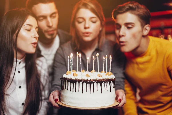 Surprise for her. Group of happy people celebrating birthday party with friends and smiling during party. Smiling attractive girl holding a cake in her hands